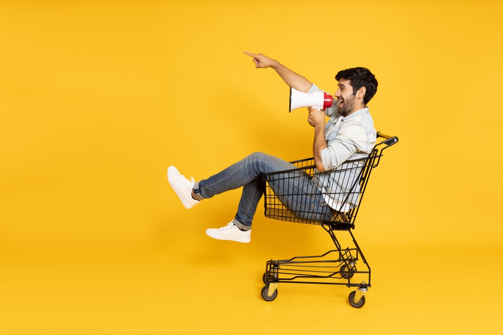 homme dans un chariot avec un megaphone sur fond jaune